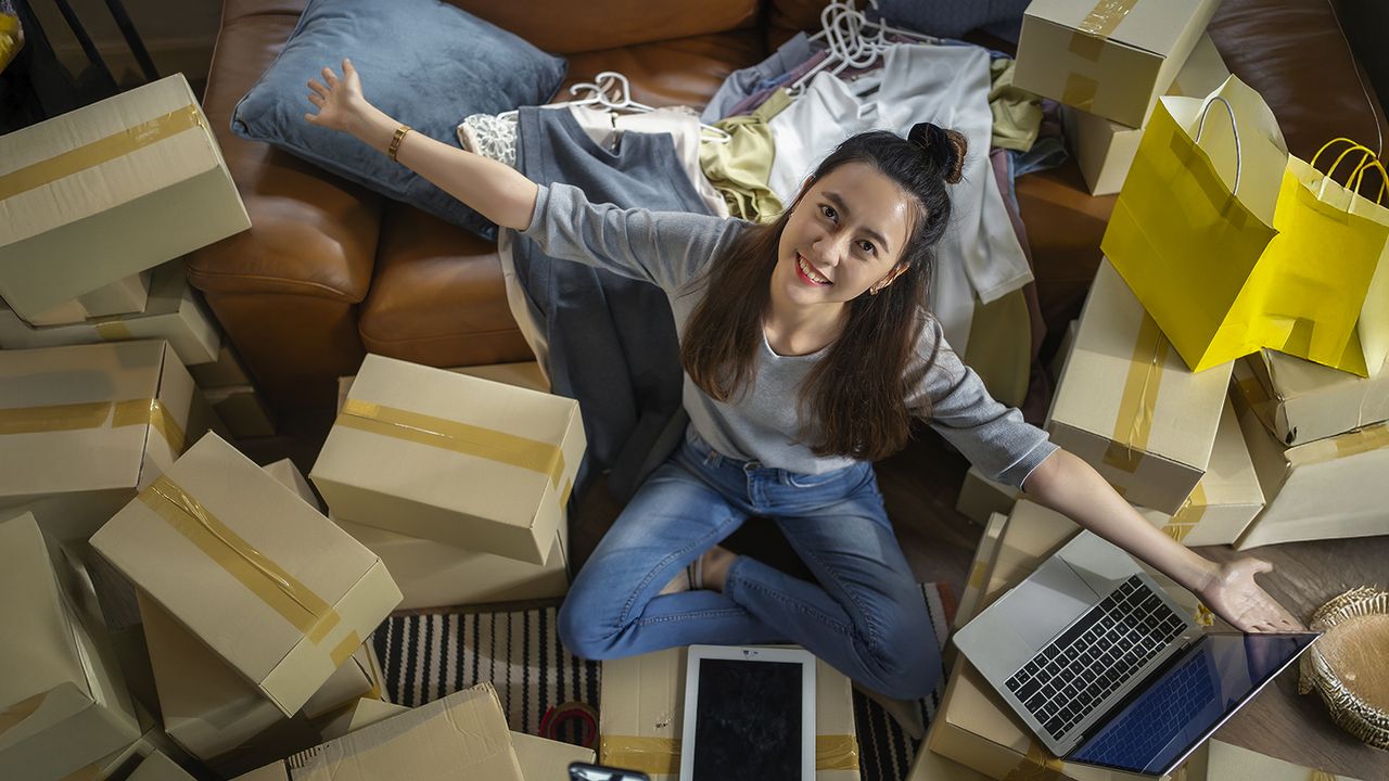 Compra múltiples productos en Amazon USA desde Ecuador Mujer rodeada de cajas y ropa tras realizar compras en Amazon USA