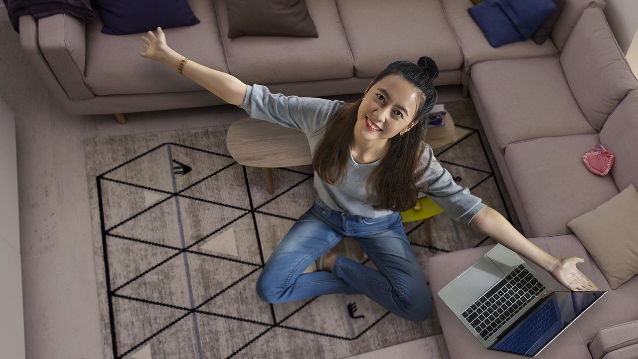 Comodidad y felicidad al comprar en Amazon USA Mujer sentada en su sala con laptop, feliz tras comprar en Amazon USA